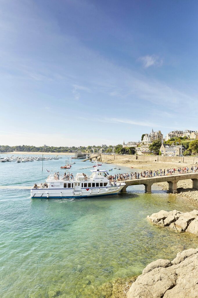 Un groupe de personne attend en ligne d'embarquer sur la navette de la Compagnie Corsaire à Dinard, sur la Promenade du Clair de Lune.