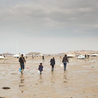 Une famille équipée de râteaux et seaux part à la pêche à pied à Dinard, en bretagne. Sur la plage du Prieuré, les amateurs de pêche à pied arrive nombreux lors des grandes marées. Cette baie s'étend à l'embouchure de la Rance, entre Dinard et Saint-Malo. Sorties nature en groupes