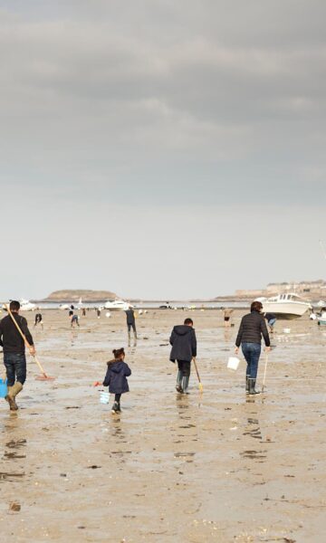 Une famille équipée de râteaux et seaux part à la pêche à pied à Dinard, en bretagne. Sur la plage du Prieuré, les amateurs de pêche à pied arrive nombreux lors des grandes marées. Cette baie s'étend à l'embouchure de la Rance, entre Dinard et Saint-Malo. Sorties nature en groupes