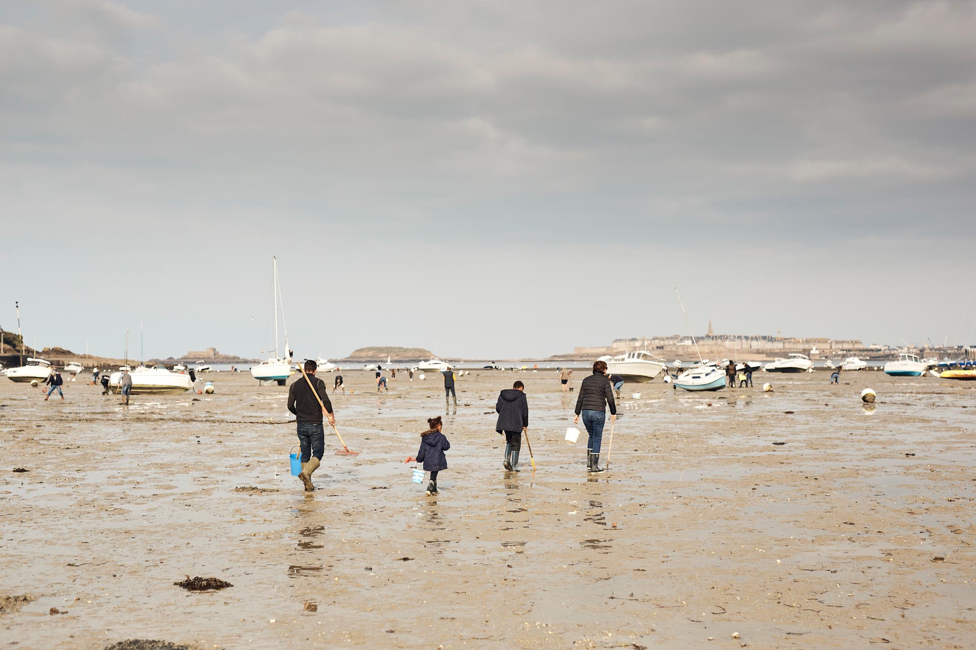 Une famille équipée de râteaux et seaux part à la pêche à pied à Dinard, en bretagne. Sur la plage du Prieuré, les amateurs de pêche à pied arrive nombreux lors des grandes marées. Cette baie s'étend à l'embouchure de la Rance, entre Dinard et Saint-Malo.