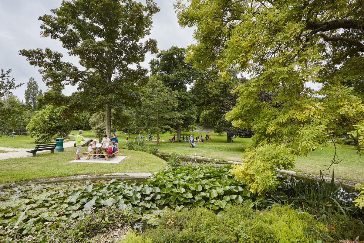 Une famille est attablée à une table de picnic au coeur du parc de Port Breton à Dinard. Ce grand espace vert est un parc public ouvert à tous et toute l'année. On peut profiter de jeux pour enfants, une roseraie, des arbres remarquables et un parc animalier.