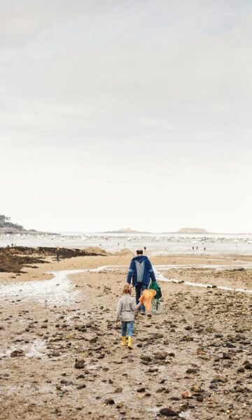 Un homme et un enfant arrivent sur la plage du Prieuré à Dinard à marée basse pour pratiquer la pêche à pied, activité nature récréative populaire en Bretagne et particulièrement appréciée lors des grandes marées.