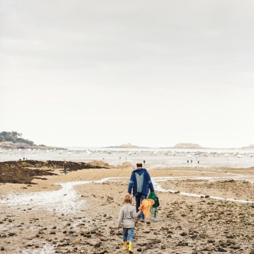 Un homme et un enfant arrivent sur la plage du Prieuré à Dinard à marée basse pour pratiquer la pêche à pied, activité récréative populaire en Bretagne et particulièrement appréciée lors des grandes marées.