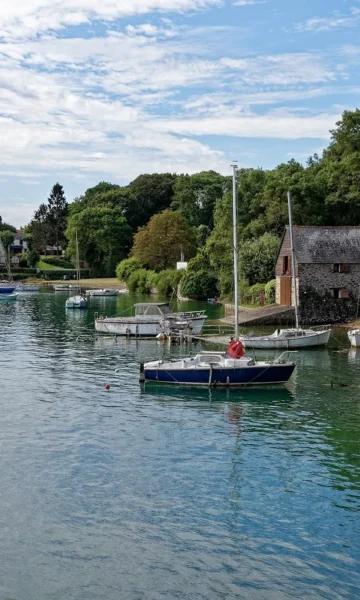 Des bateaux sur l'eau devant la cale de la Landriais au Minihic-sur-Rance, sur les bords de l'estuaire de la Rance.