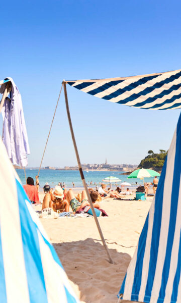 La Plage De L'ecluse à Dinard et ses emblématiques tentes rayées pour profiter des joies de la plage à l'ombre du soleil.