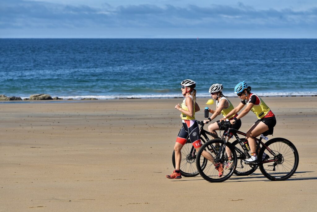 trois athlètes en pleine action durant l'Emeraude Tri Race sur la plage de Longchamp, concentré et dynamique, reflétant l'esprit sportif et la détermination face à l'épreuve.