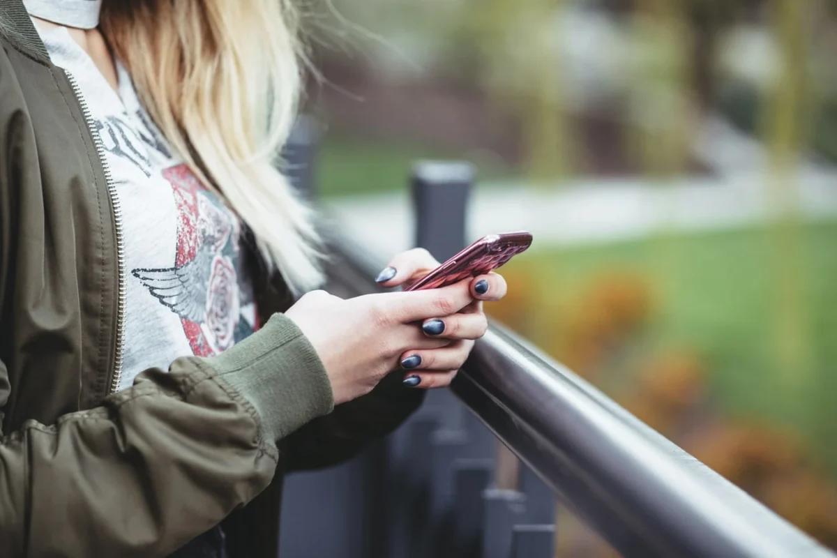 Une femme joue au géocaching sur son smartphone avec l'application gratuit Trésors de Haute Bretagne. De nombreuses quêtes à terminer sur la côte d'Emeraude.