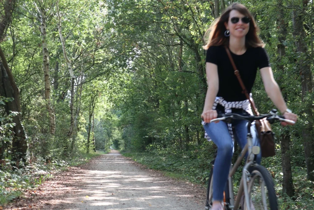 Une femme se promène à vélo sur la voie verte V42 qui relie Dinan à Dinard, à hauteur de Tréméreuc. Une voie verte ombragée et sécurisée.