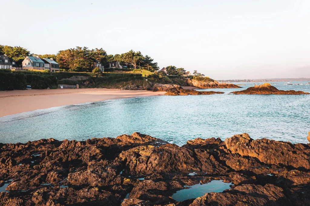 Photo de la plage du Rocher à Lancieux avec une lumière douce. La plage est paisible et vide. La mer est haute. 