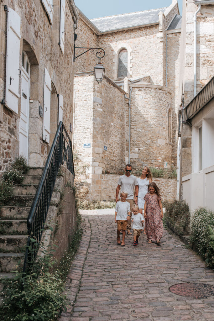 Une famille se promène dans Les Venelles De Saint Briac, au milieu des anciennes maisons de marins.