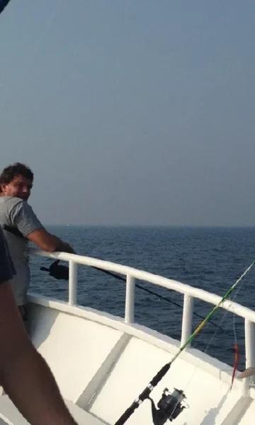 Deux hommes tiennent une canne à pêche sur un bateau lors d'une activité pêche en mer organisée par la Compagnie Corsaire au départ de Dinard et Saint-Malo.