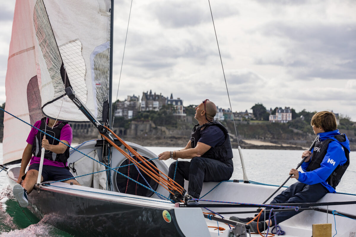 Une famille tient la barre d'un voilier dans la baie de Dinard. La Côte d'Émeraude est un terrain de jeu parfait pour les amateurs d'activités nautiques en Bretagne.