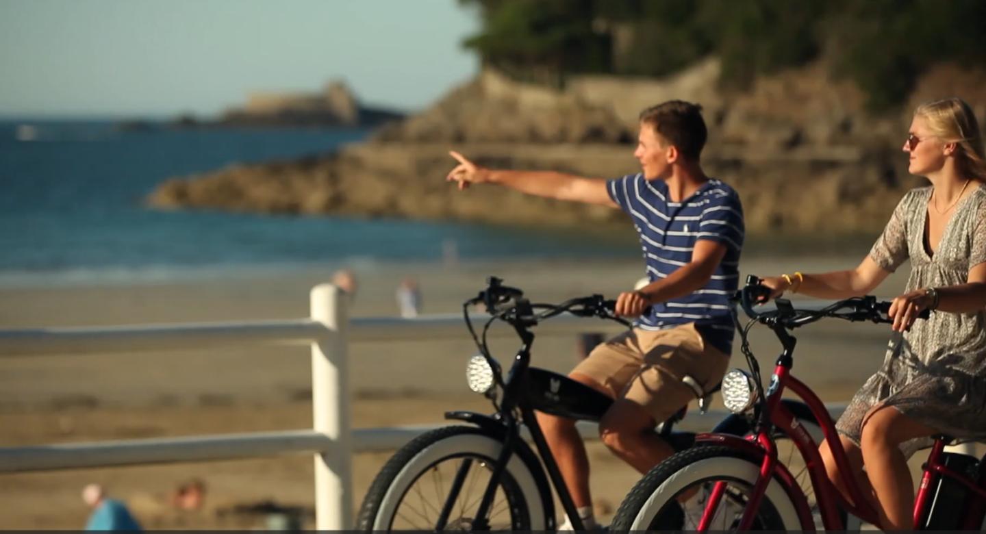 Deux ados font du Vélo à Dinard, sur le bord de la plage.