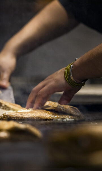 Un maître crêpier cuisine une galette de sarrasin. la photo zoom sur ses mains.