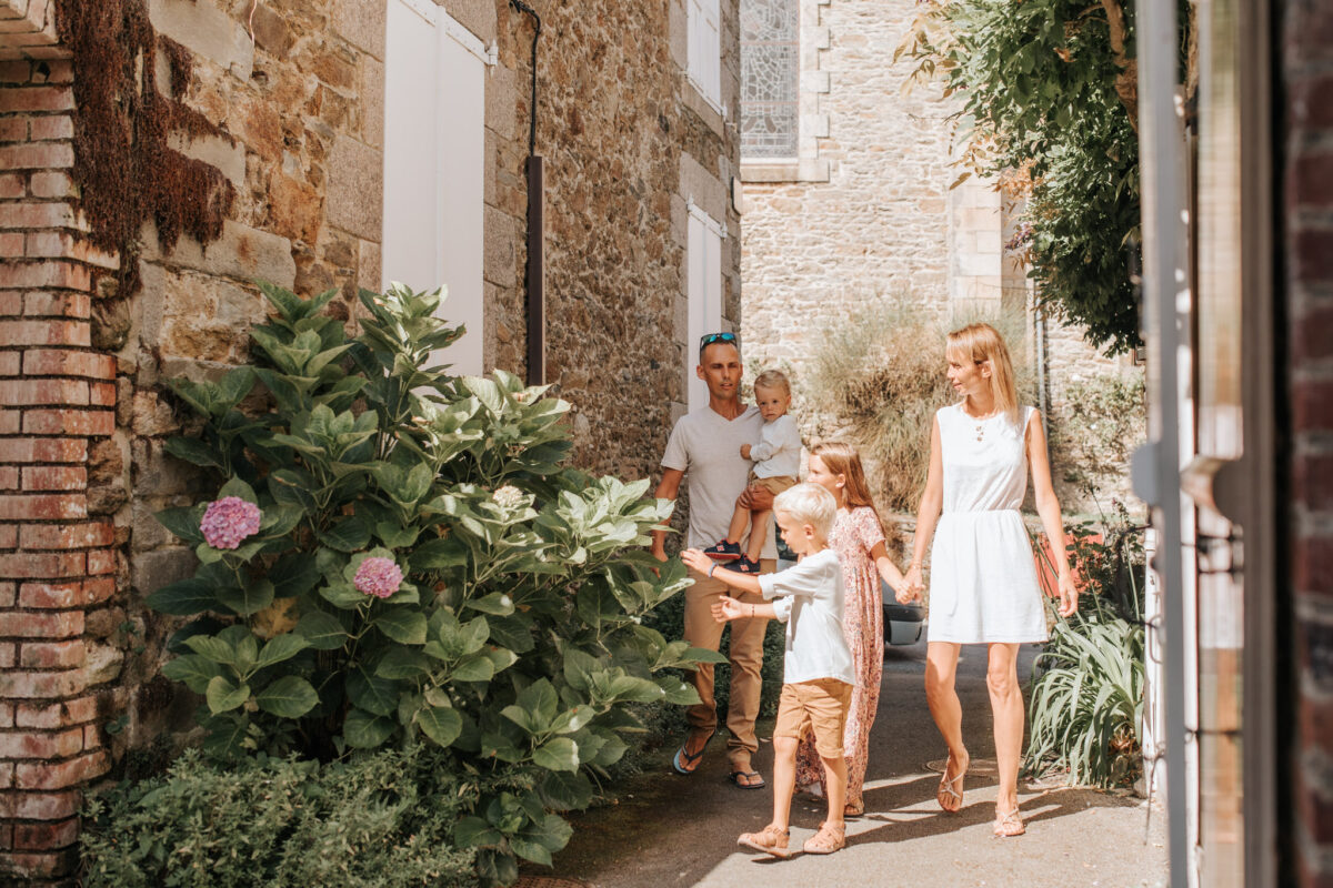 Famille qui marche dans les venelles de Saint-Briac-sur-mer. Il fait très beau et la végétation est présente dans les rues.