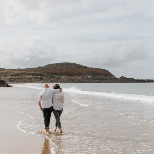 Scène romantique. Un couple marche sur la plage de Longchamp à Saint-Lunaire les pieds dans l'eau.