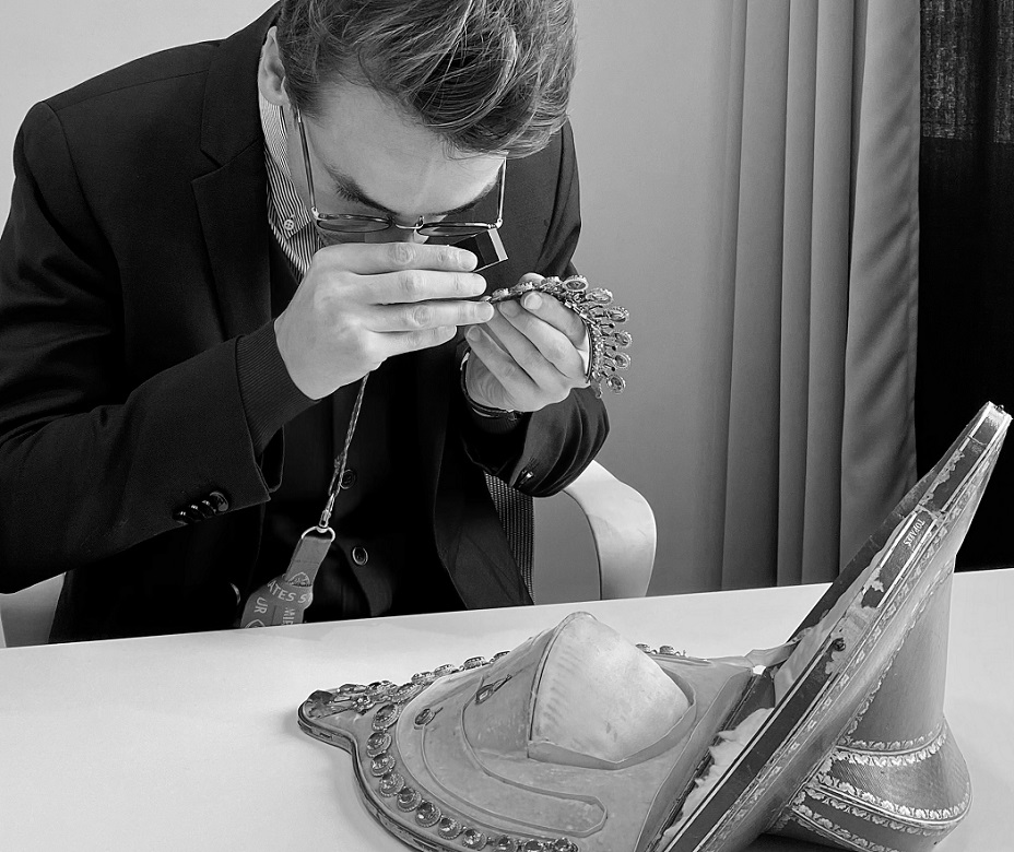 Rossini Maison De Vente Aux Enchères à Dinard. Un homme examine un bijou dans le but de l'estimer.