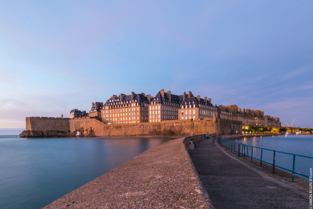 Que visiter aux alentours de Dinard ? La cité corsaire de Saint Malo et les remparts au coucher du soleil. Photo de Simon Bourcier