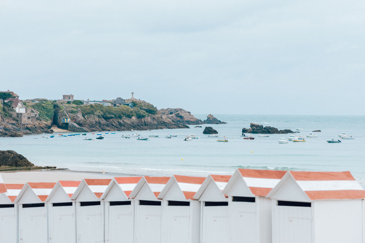 Saint-Lunaire et ses cabines de plage sur la Grande Plage. Vue sur la croix de la Pointe du Décollé. Crédit photo : Loeildeos